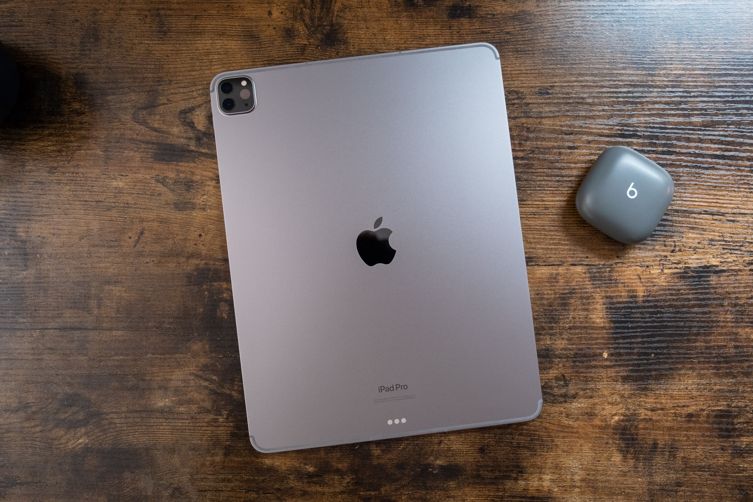 A 12.9-inch space gray iPad Pro face down on a wooden table, viewed from the top down.
