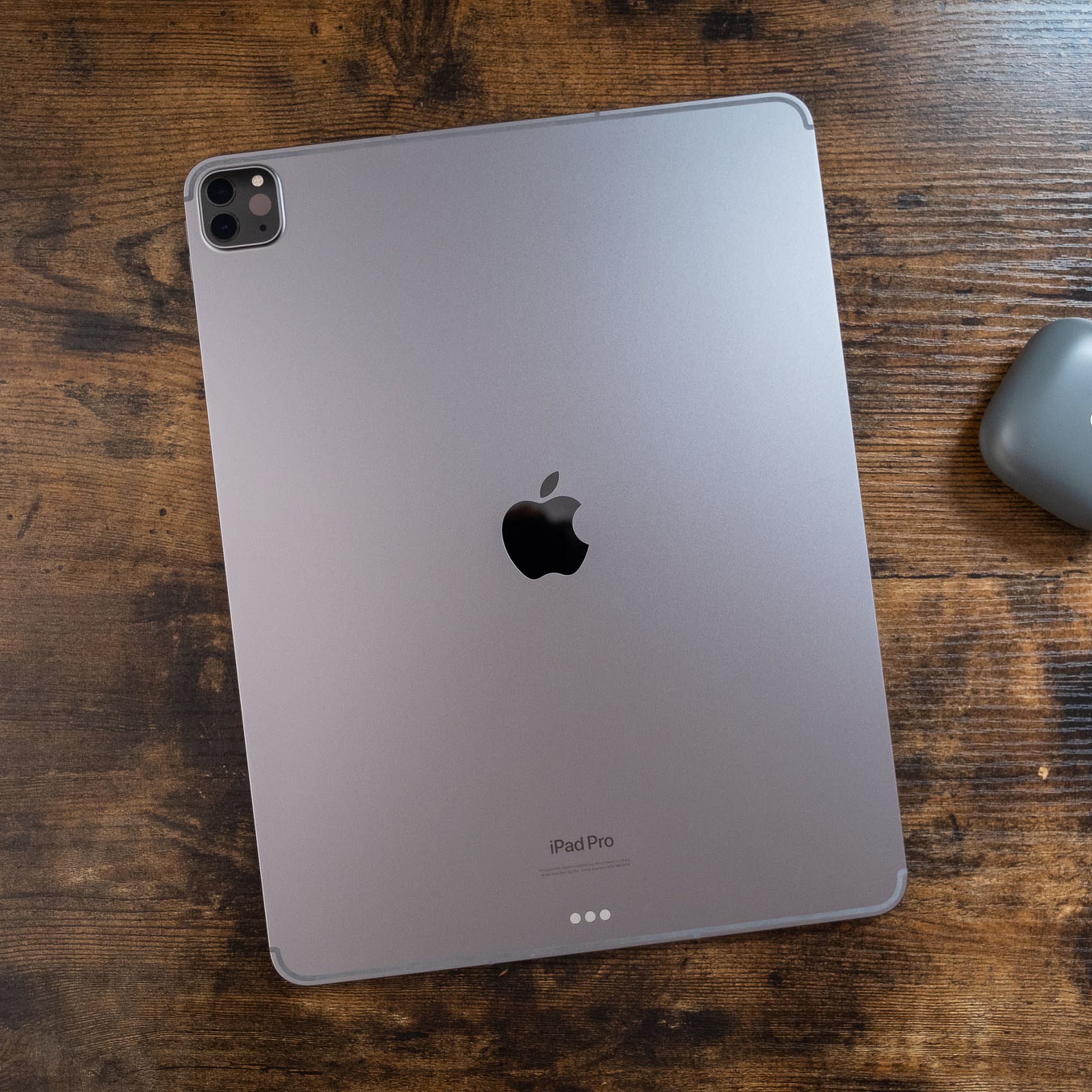 A 12.9-inch space gray iPad Pro face down on a wooden table, viewed from the top down.